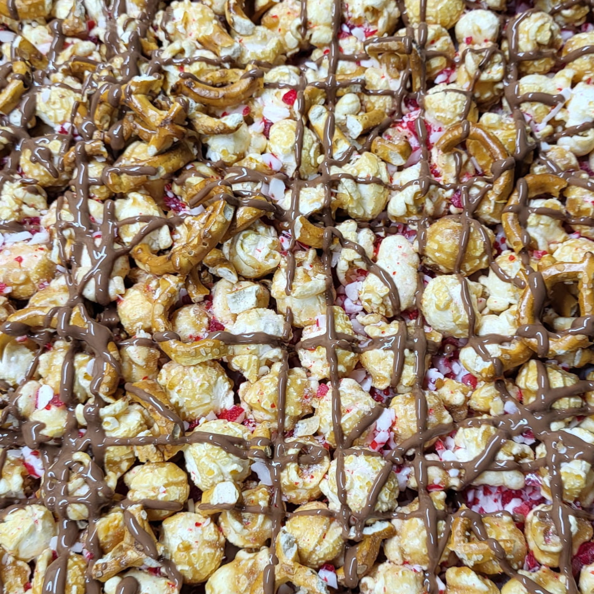Close up of Reindeer Munch popcorn with pretzels, crushed candy cane and Callebaut milk chocolate drizzles over top